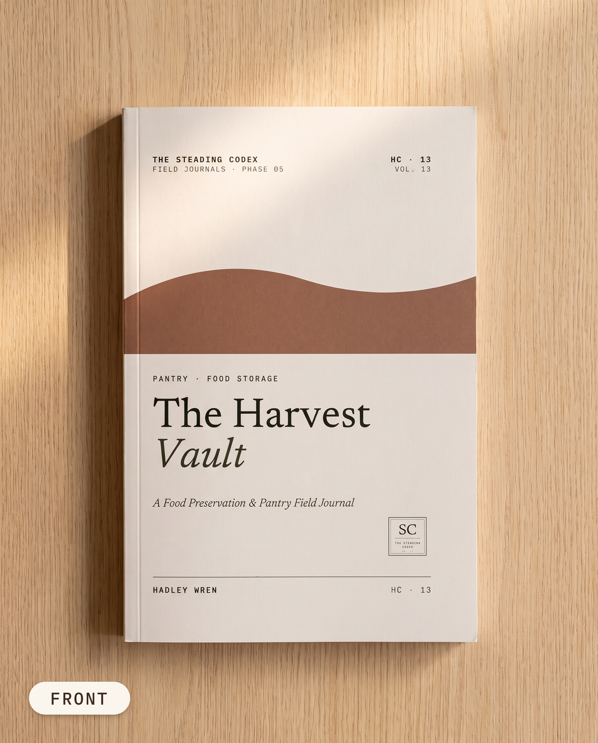 The Harvest Vault pantry and food storage journal — front cover on an oak table